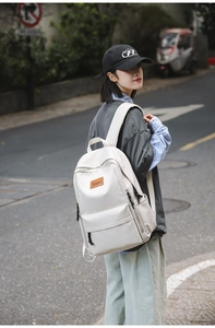 Outdoor shot of a minimalist white nylon backpack featuring the Tengrun leather logo