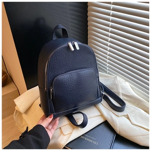 Detailed view of navy blue pebbled leather backpack with silver metal zippers and pocket