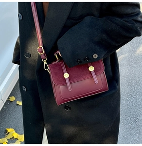 Detail of vintage burgundy shoulder bag with gold buckles on a black wool coat