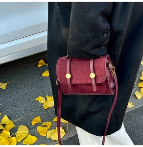 Retro burgundy crossbody bag styled with a black wool coat over autumn ginkgo leaves