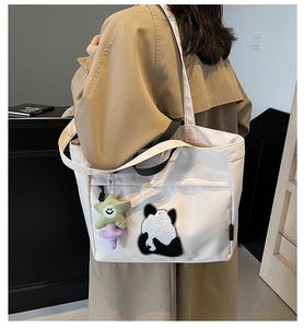Borsa tote bianca con ricamo panda e ciondolo a stella indossata sulla spalla