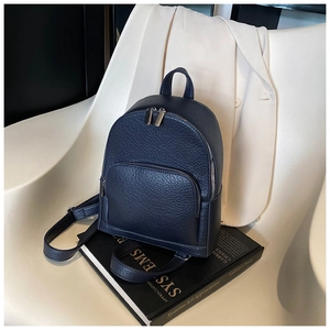 Detail of navy blue pebble leather backpack with silver zippers on art books