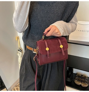 Detail of burgundy vintage crossbody bag with gold buckles and dual texture finish