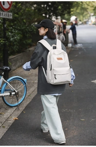 Outdoor lifestyle shot of a cream white minimalist laptop backpack for college students