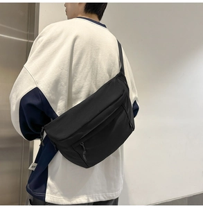 Side view of large black nylon crossbody bag featuring wide adjustable strap on model
