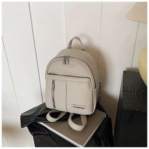 Detail of beige lychee grain leather mini backpack with metal logo and front zipper