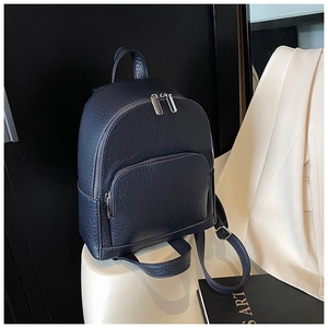 Detail of pebbled leather backpack showing silver zippers and premium texture