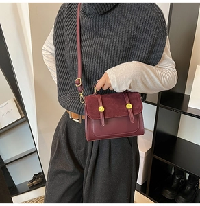 Detail of burgundy leather crossbody bag with gold metal buckles and adjustable strap