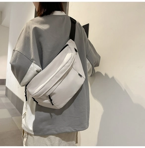 Rear view of model wearing a minimalist cream crossbody chest bag with adjustable strap