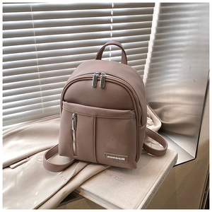 Detail of taupe pebbled leather backpack with metallic zippers and branded label