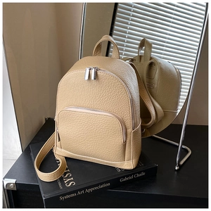 Detailed close-up of beige lychee texture leather mini backpack with dual zip pockets