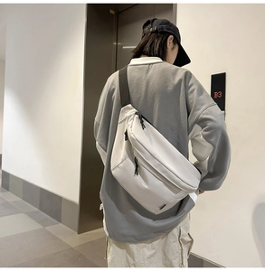 Rear view of a white high-density crossbody bag with black wide straps on a person