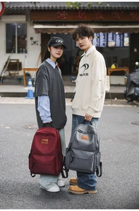 Close-up of burgundy and grey minimalist backpacks with premium leather logo detail