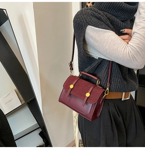 Detailed view of burgundy vintage crossbody bag with gold buckle on a stylish model