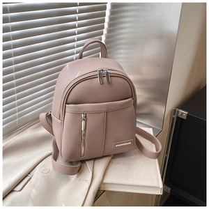 Detail of elegant beige pebbled leather backpack with metal logo and front zipper pocket