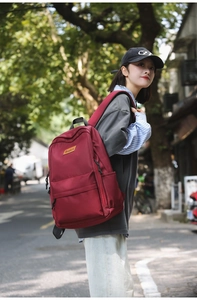 Detailed side view of a dark red nylon laptop backpack worn by a student outdoors