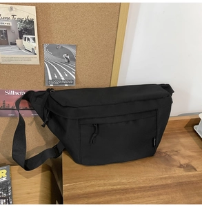 Close-up of black canvas crossbody bag with hidden zipper pocket on a wooden desk