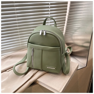 Detail of light green pebble-grain faux leather backpack with double zippers and metal logo