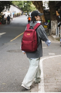Close-up of a student wearing a burgundy water-resistant laptop backpack on a city street