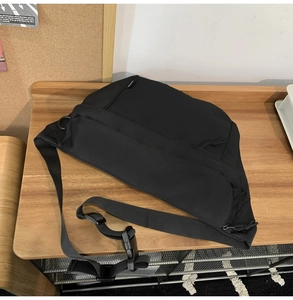 Close-up of black nylon messenger bag featuring adjustable straps and zipper details