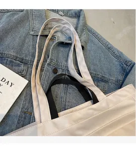 Dettaglio dei doppi manici robusti della borsa tote in tela e cuciture rinforzate su denim