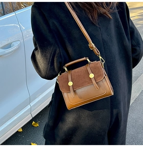 Detail view of brown vintage satchel showing suede texture and gold metal buckle