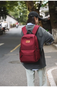 Detail shot of a dark red nylon backpack with adjustable straps and front zip pocket