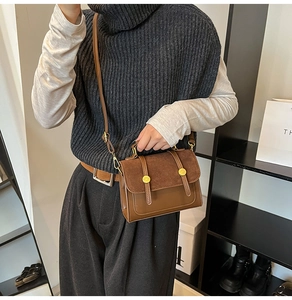 Detail of vintage crossbody bag showing contrast brown leather and metal buckle texture