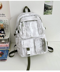 Detail of canvas backpack with grey ink calligraphy and green straps in a desk setting