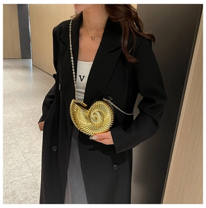 Detail of golden nautilus shell clutch with metallic texture on a black blazer
