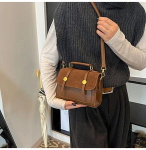 Detail of a brown crossbody bag with suede flap and gold buckle on a shoulder model