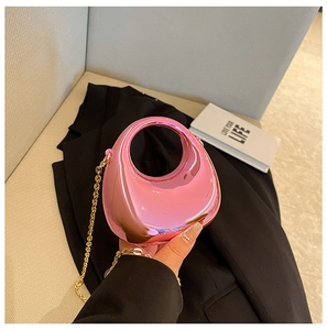 Detalle del bolso de noche de acrílico rosa metálico con una elegante cadena dorada