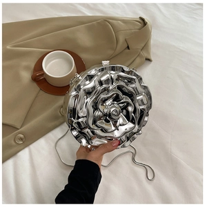 Artistic silver rose flower metal evening bag with long chain shown in a lifestyle setting