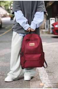 Close-up of wine red nylon backpack with TENGRUN logo patch and durable zipper details