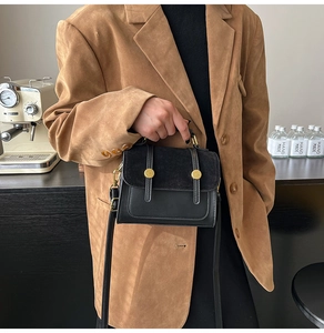 Detail of black leather crossbody bag with suede patchwork and gold buckle hardware