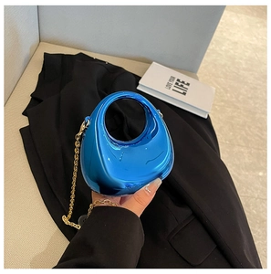 Detalle del bolso de acrílico azul metálico con asa circular y cadena dorada