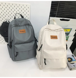 Detail showing two high-capacity nylon backpacks in grey and cream with brand logo