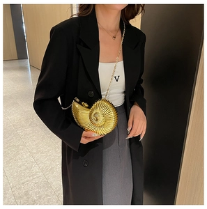 Detailed view of snail shaped golden acrylic clutch bag with metallic wavy texture and chain