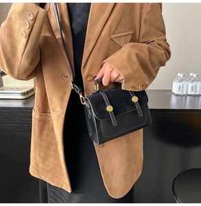 Detail of vintage black crossbody bag featuring matte leather flap and gold buckles
