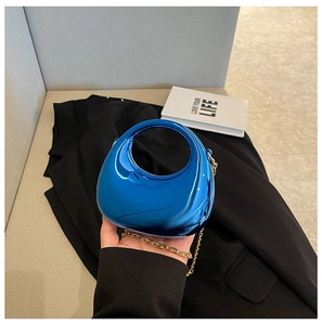 Detalle de mini bolso de acrílico azul eléctrico con cadena dorada y asa circular