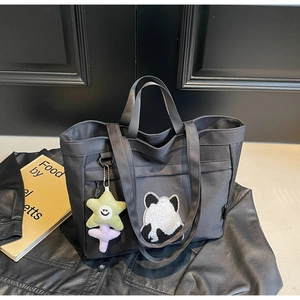 Dettaglio borsa tote in tela nera con toppa panda e ciondolo a stella e fiori