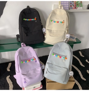 Detail of Korean style backpacks in black, beige, purple and grey with cute plush charms