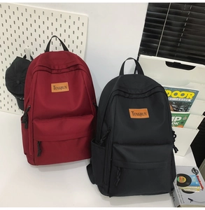 Detail view of red and black school backpacks with front pockets and brand logo patch