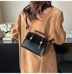 Detail of vintage crossbody bag showing black leather and suede texture with gold hardware