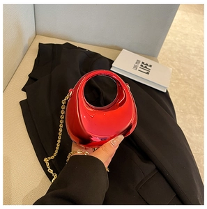 Detalle de mini bolso acrílico rojo metalizado con asa curva y cadena dorada fina