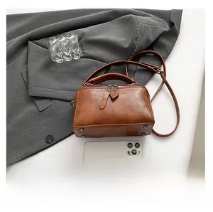 Detail view of brown PU leather boston bag showing dual zippers and metal bottom studs