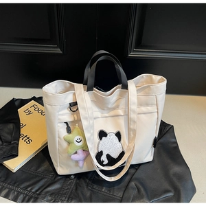 Dettaglio della borsa tote in tela beige con patch panda e ciondolo a stella colorato