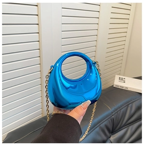 Detalle de bolso medialuna azul metálico con asa integrada y fina cadena dorada