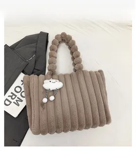 Detail of brown plush tote bag with vertical stripes and spherical handle design
