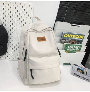 Detail of minimalist beige backpack with brown leather logo and multiple utility pockets